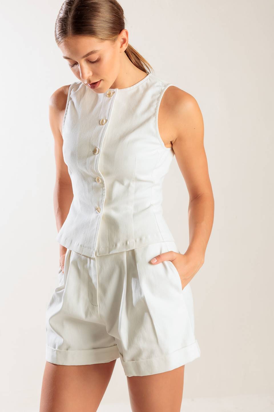 A sleeveless, solid white woven vest featuring a round neckline and front button down.