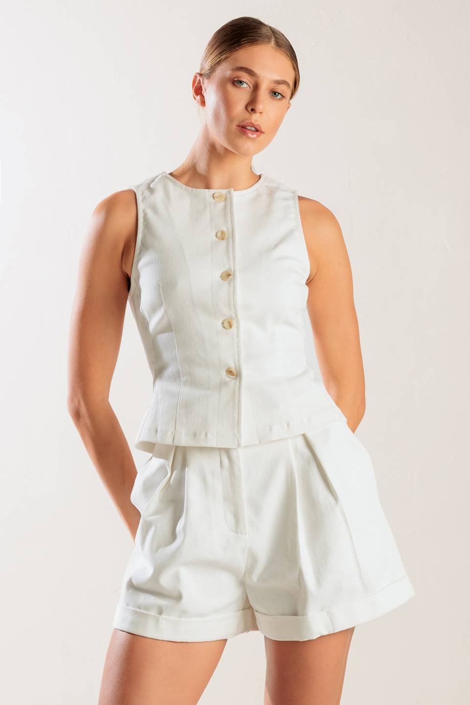 A sleeveless, solid white woven vest featuring a round neckline and front button down.