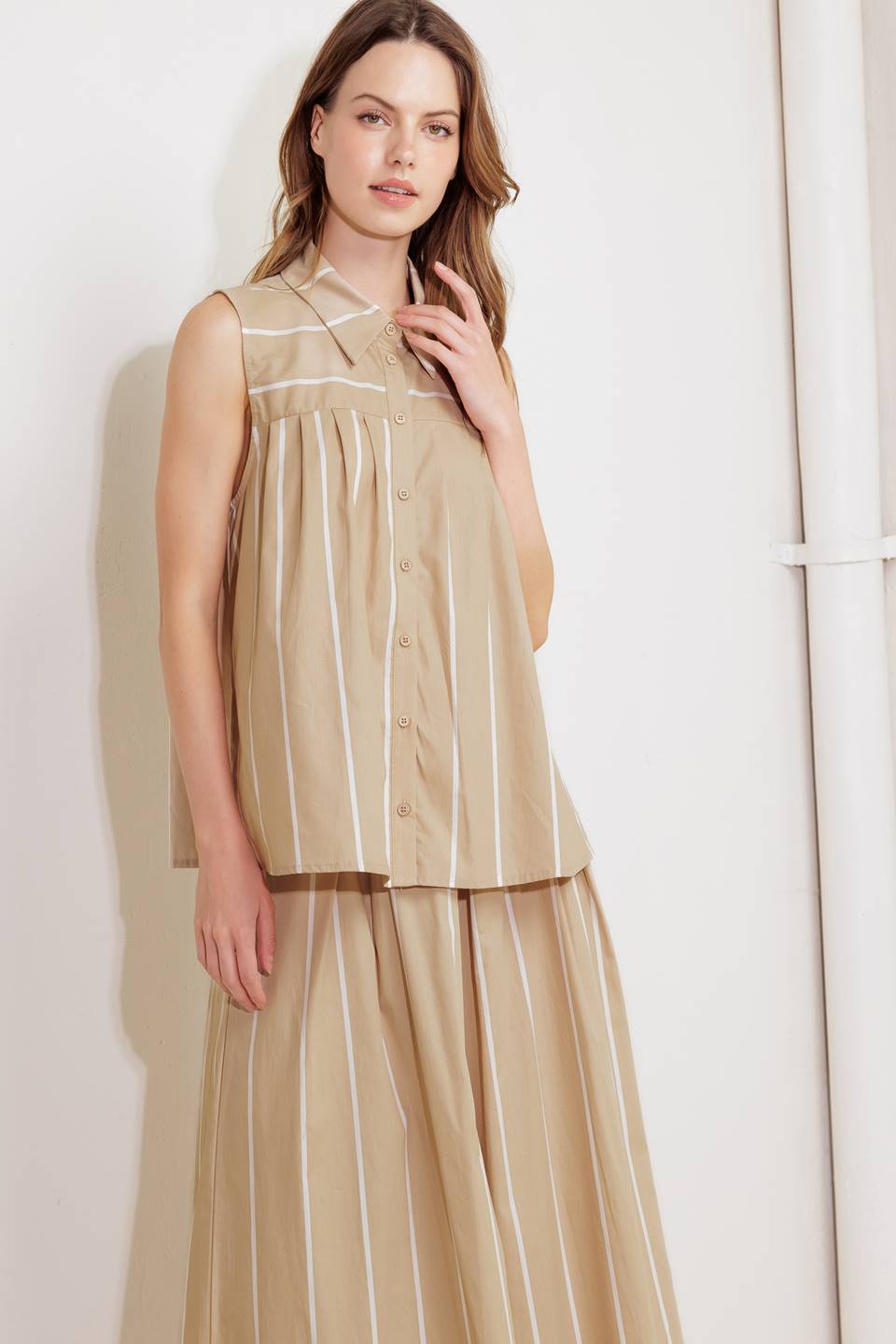 A striped woven top featuring collar, sleeveless, button down and pleated front and back.