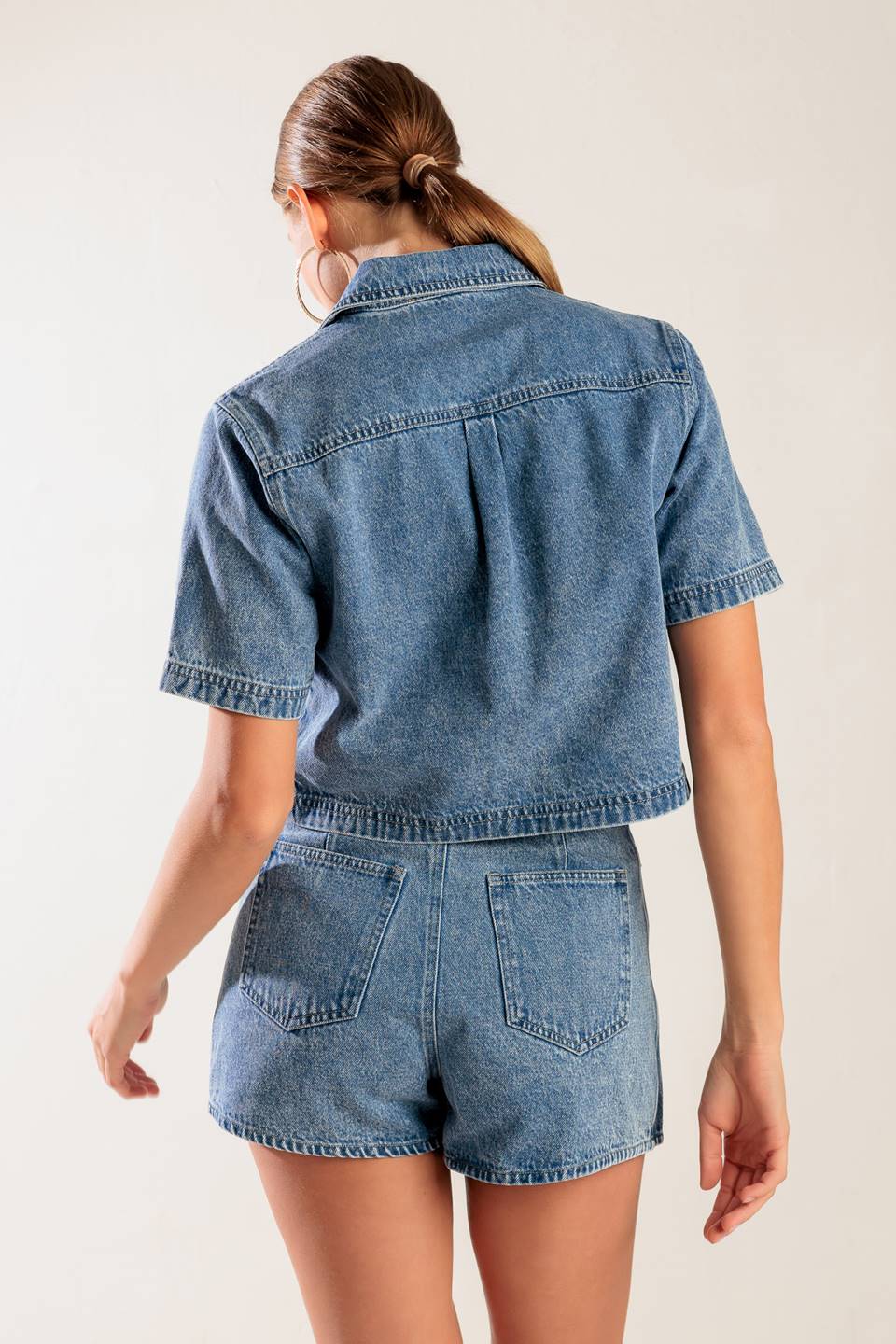 A washed denim top featuring collar, open front with bow ties, short sleeve and pockets.