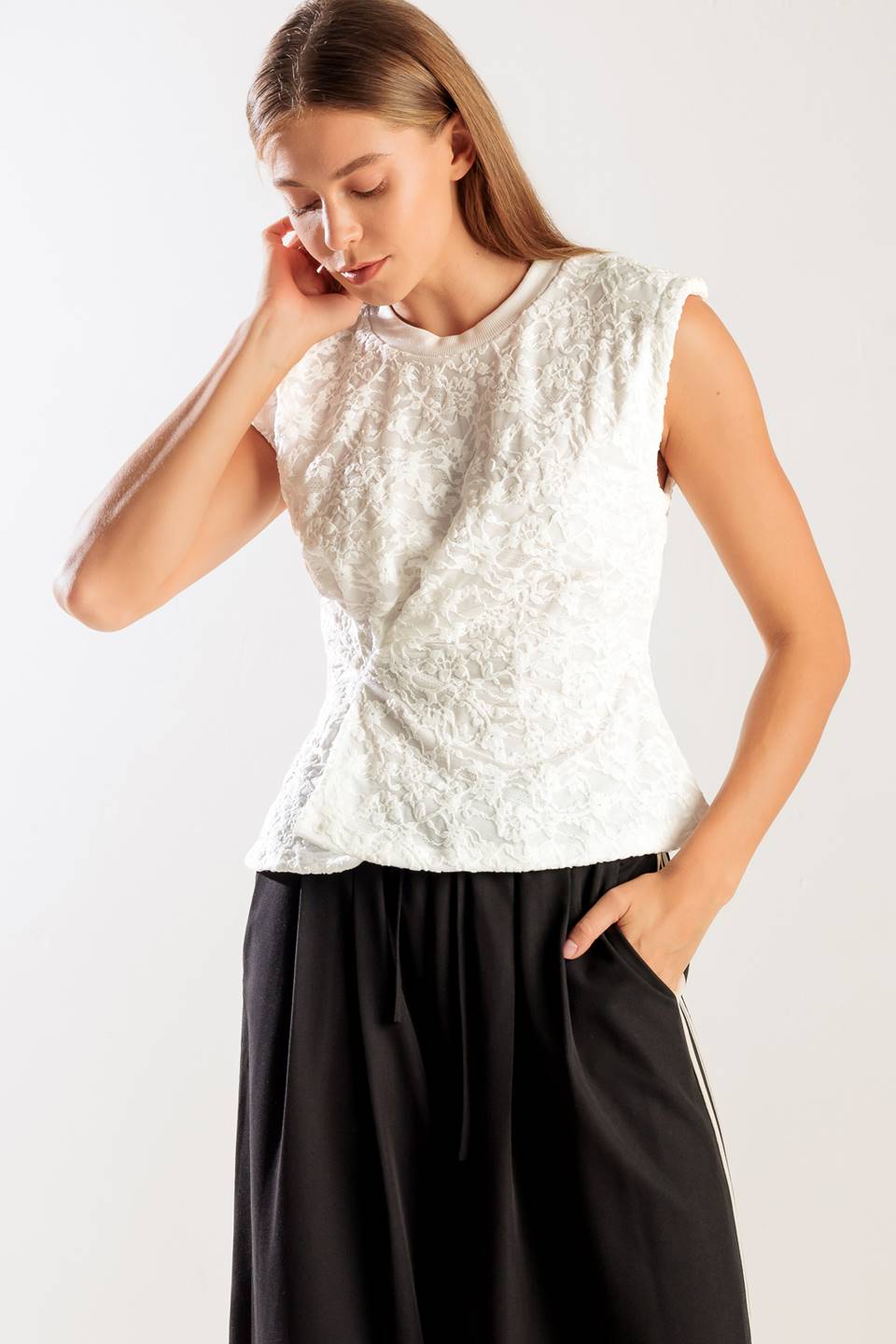 A sleeveless white woven lace top featuring a round neckline and cinched front