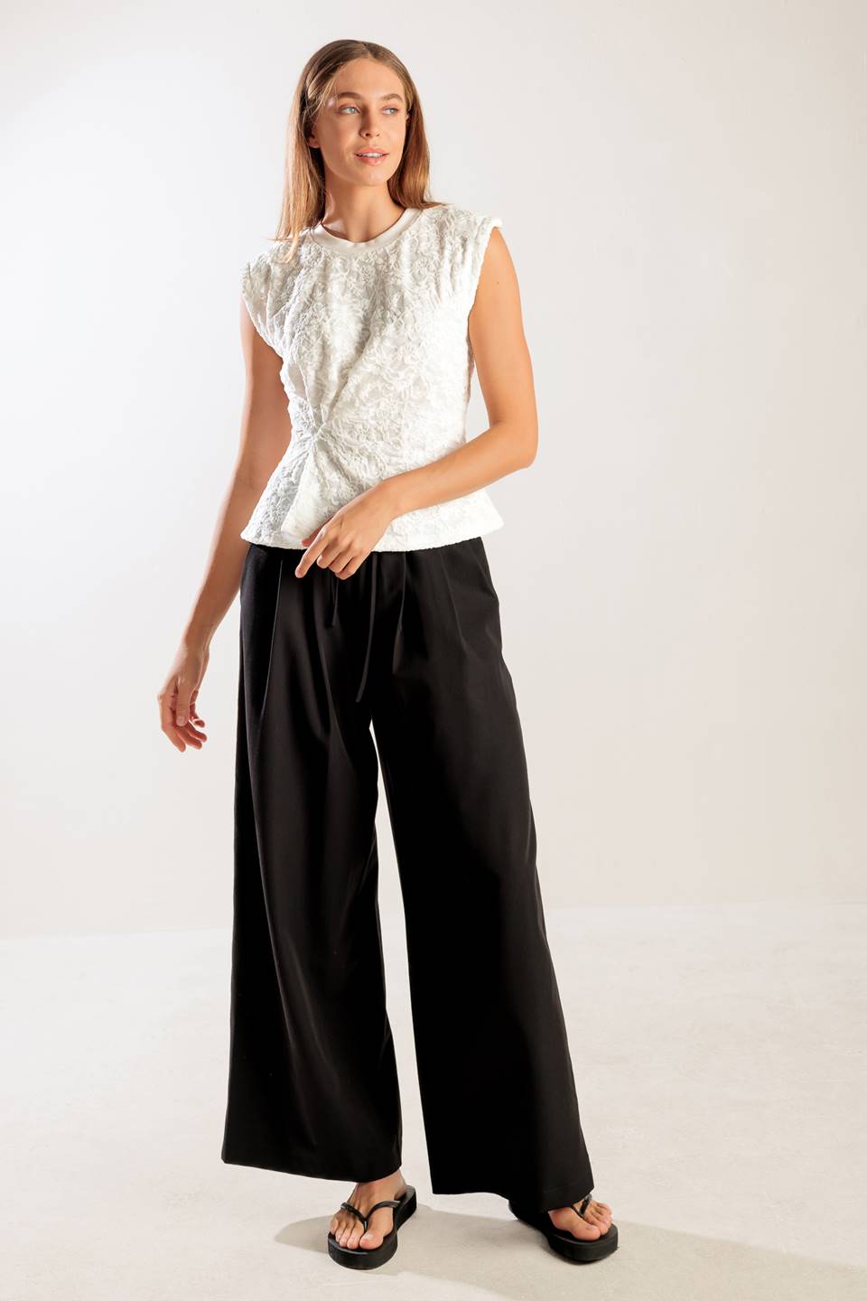 A sleeveless white woven lace top featuring a round neckline and cinched front