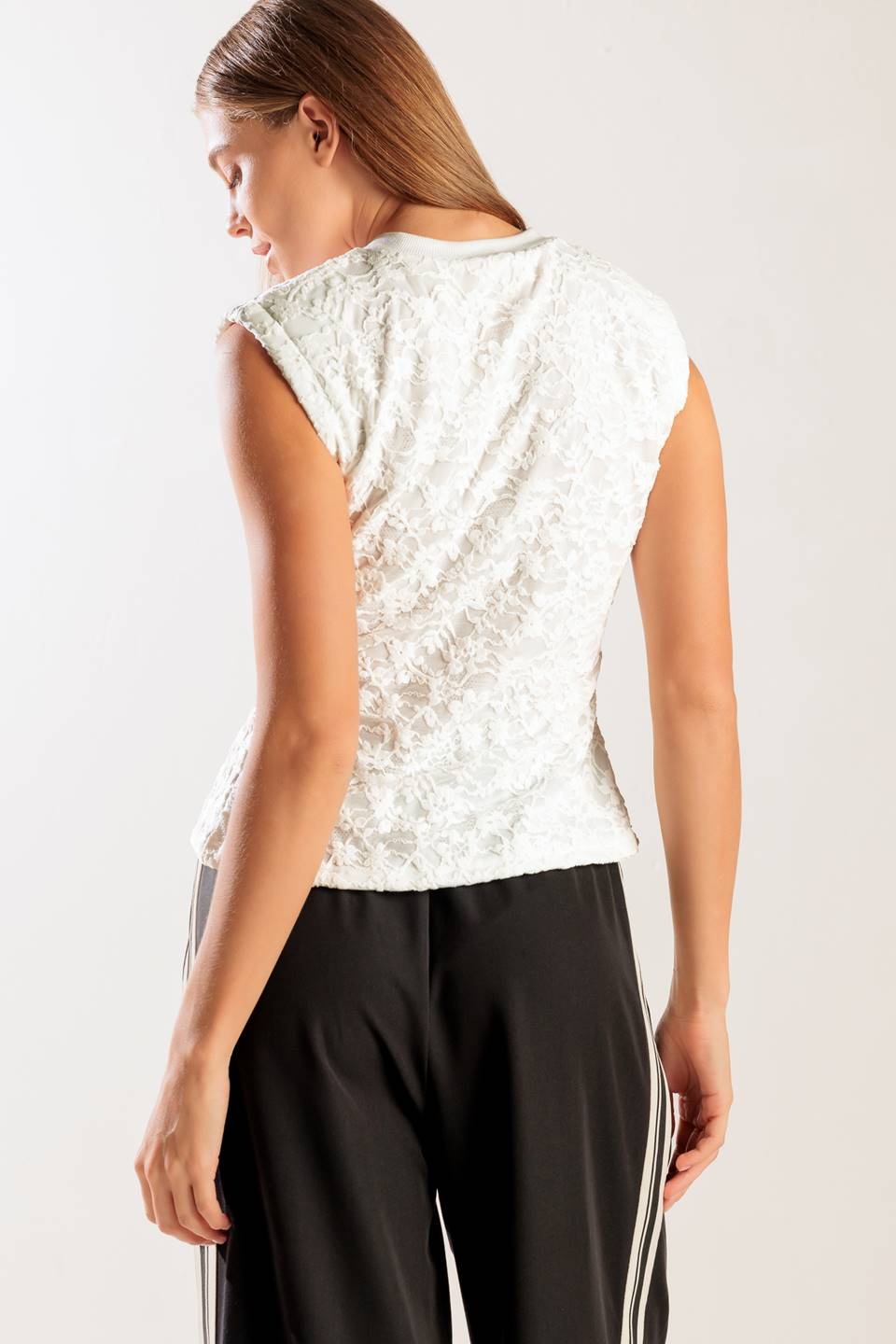 A sleeveless white woven lace top featuring a round neckline and cinched front