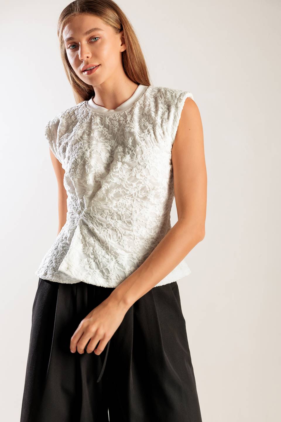 A sleeveless white woven lace top featuring a round neckline and cinched front