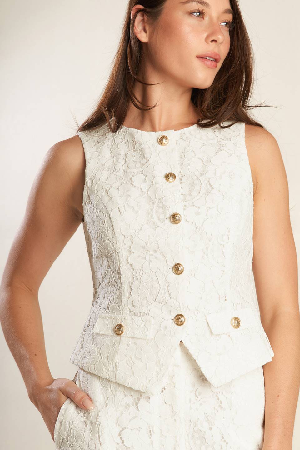 A white sleeveless woven lace vest featuring round neckline and button down.