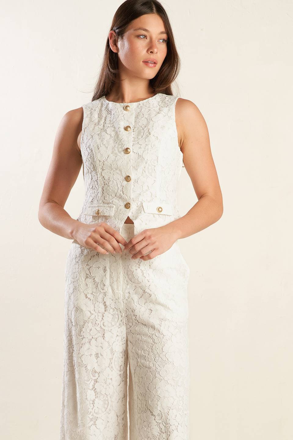 A white sleeveless woven lace vest featuring round neckline and button down.