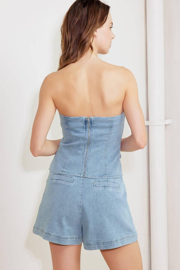A washed denim top featuring strapless, front button-down detail and back zipper closure.