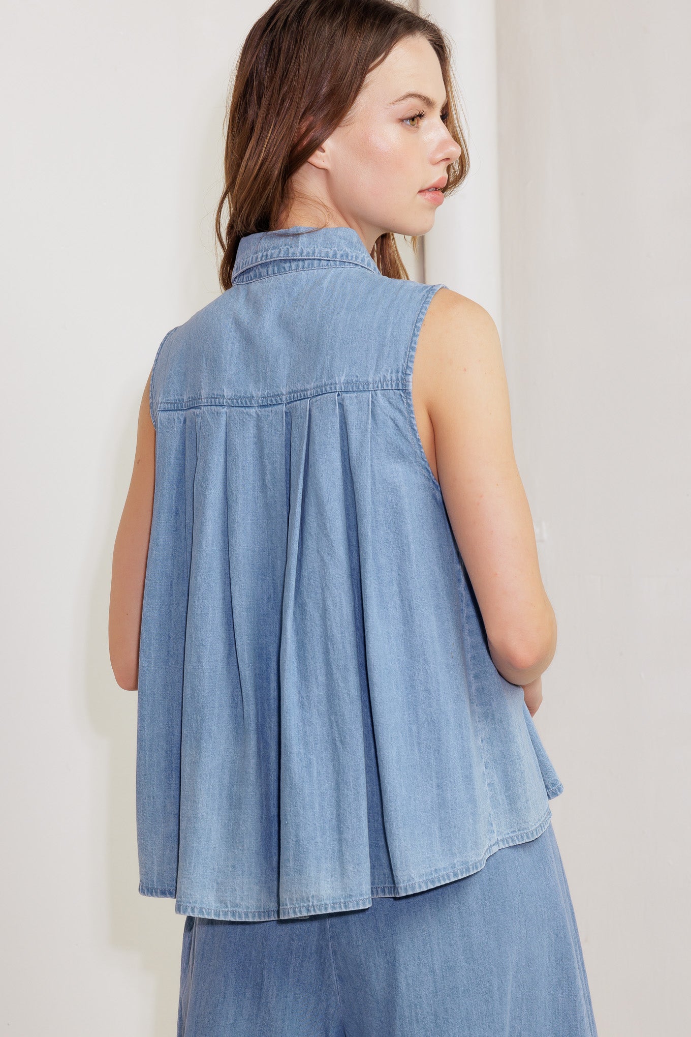 A washed chambray to featuring collar, button down, sleeveless and pleats.