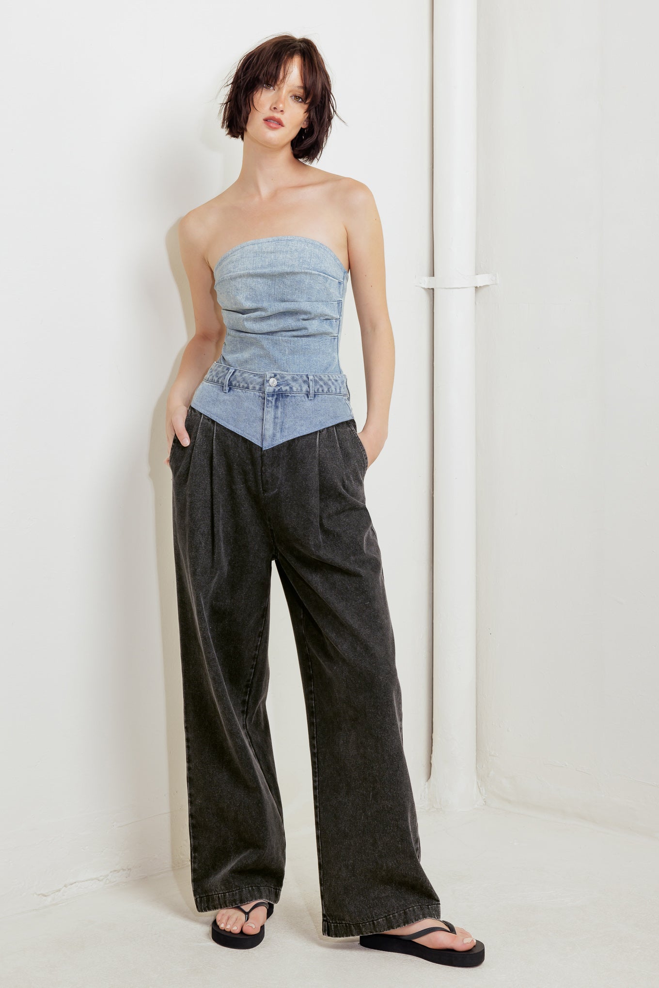 An acid-washed denim bodysuit featuring strapless, side shirring and bottom snap button closure