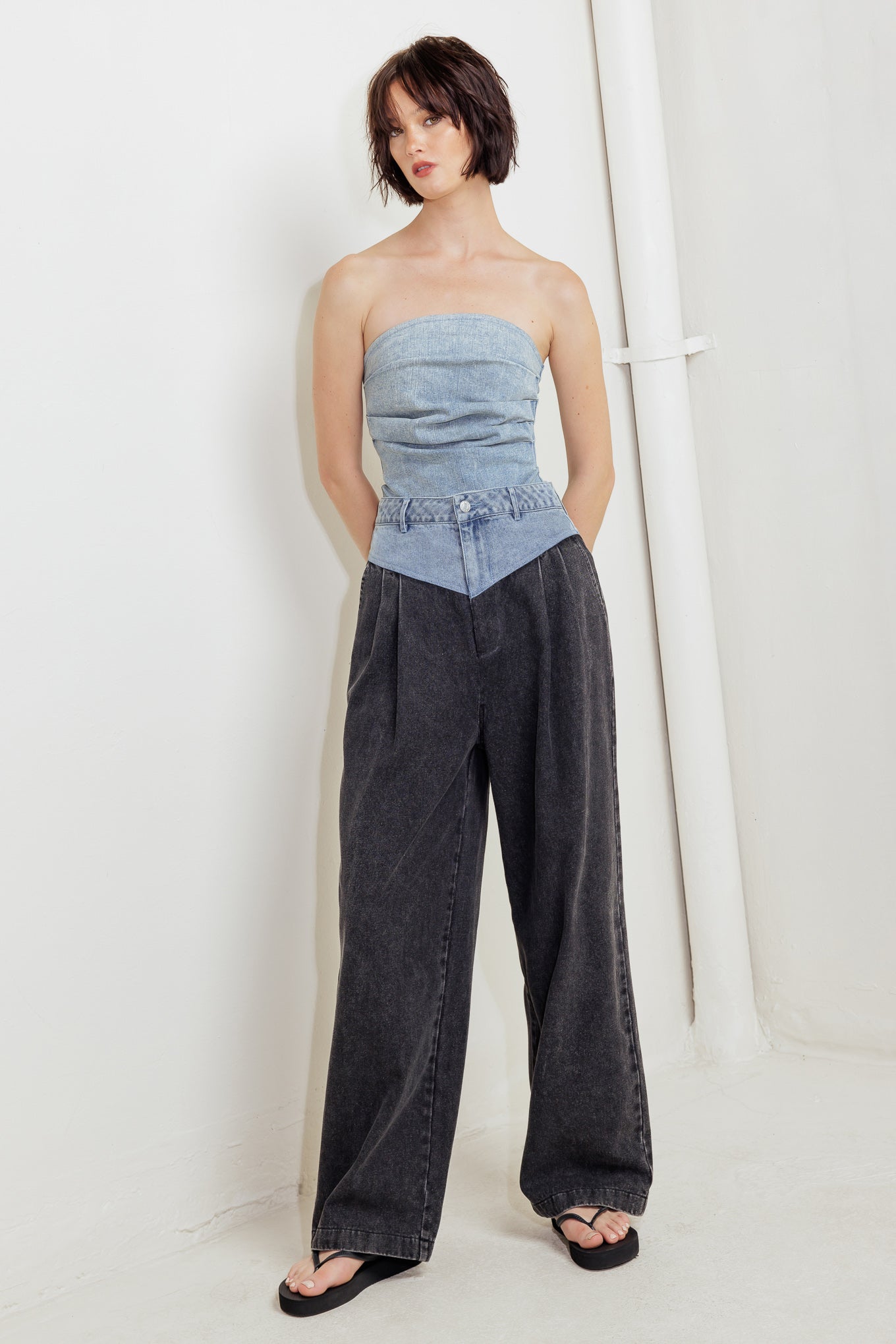 An acid-washed denim bodysuit featuring strapless, side shirring and bottom snap button closure