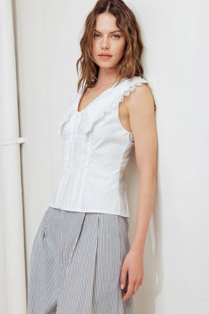 A solid woven top featuring V neckline, peter pan collar with lace trim, sleeveless, pin tuck front and button down closure