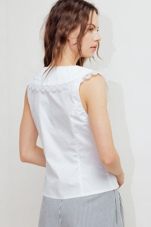 A solid woven top featuring V neckline, peter pan collar with lace trim, sleeveless, pin tuck front and button down closure