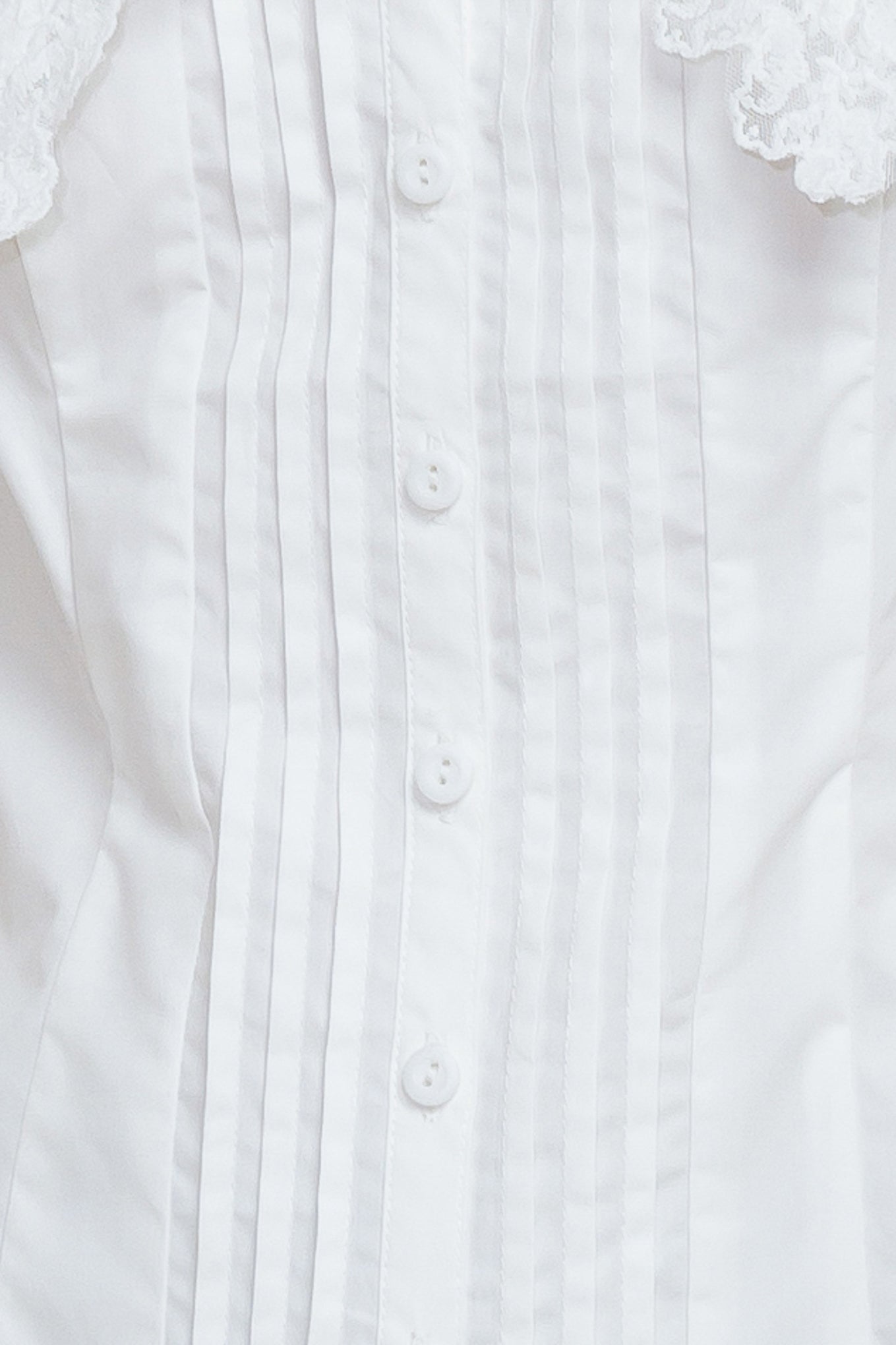 A solid woven top featuring V neckline, peter pan collar with lace trim, sleeveless, pin tuck front and button down closure
