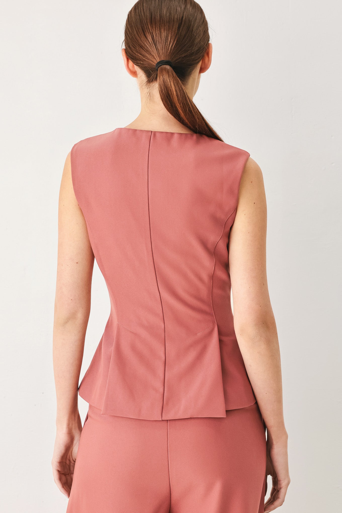 Woman wearing a pink mauve solid woven top featuring round neckline, sleeveless, peplum and front zipper closure | FREEMARKET