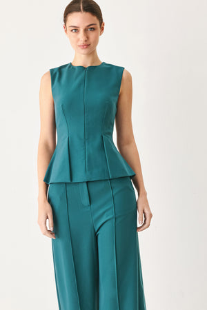 Woman wearing a teal solid woven top featuring round neckline, sleeveless, peplum and front zipper closure | FREEMARKET