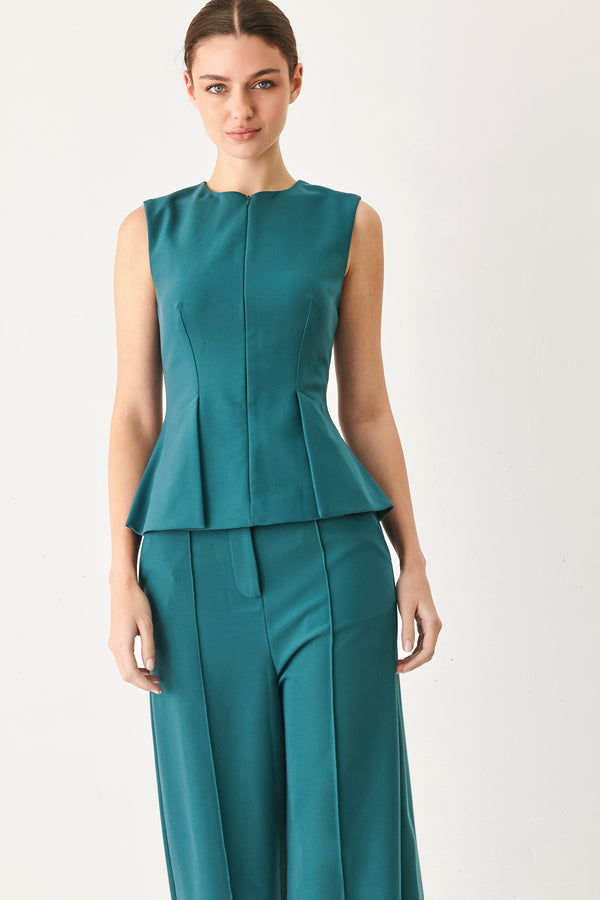 Woman wearing a teal solid woven top featuring round neckline, sleeveless, peplum and front zipper closure | FREEMARKET