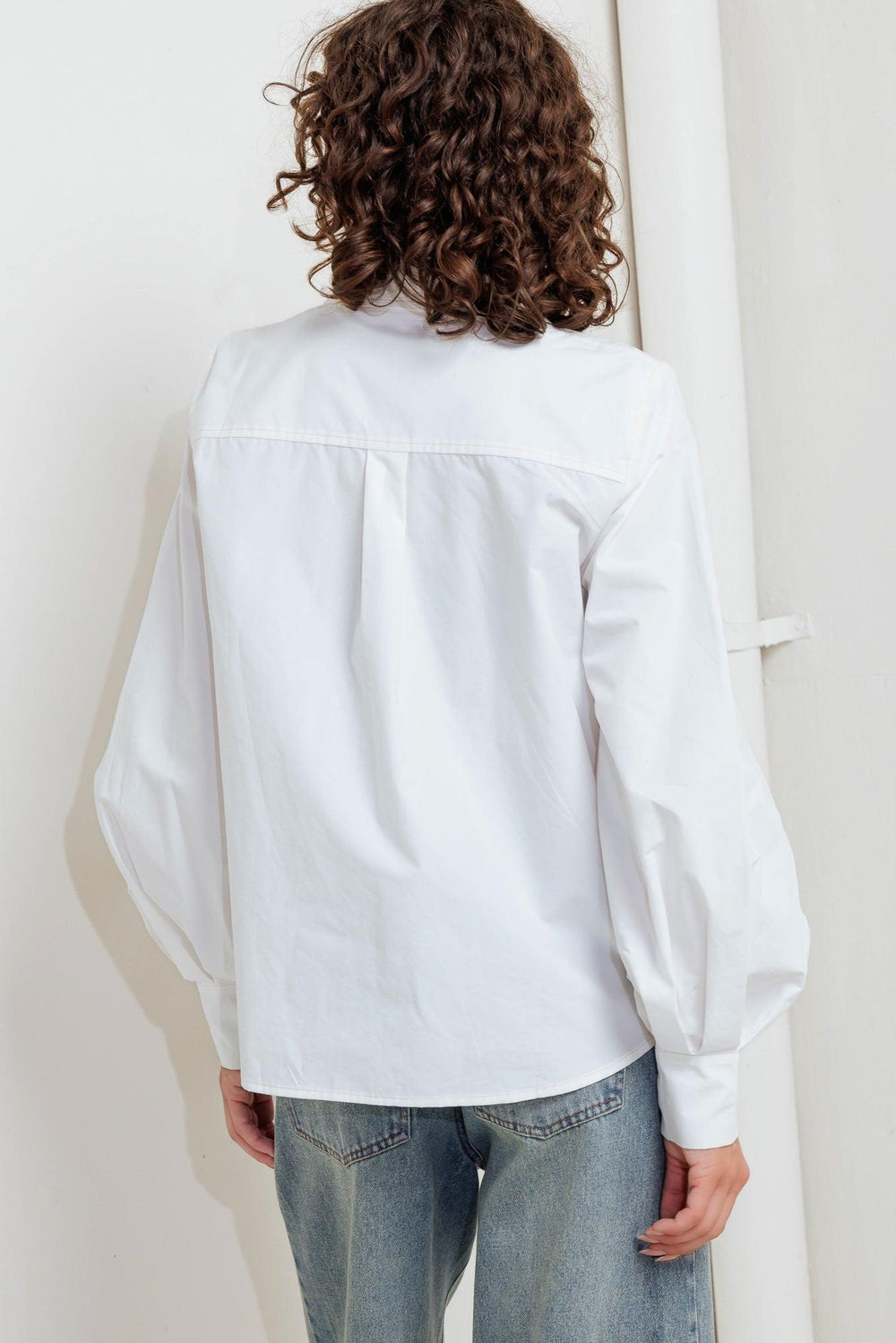 A solid white woven top featuring collar, front snap button down and long sleeve