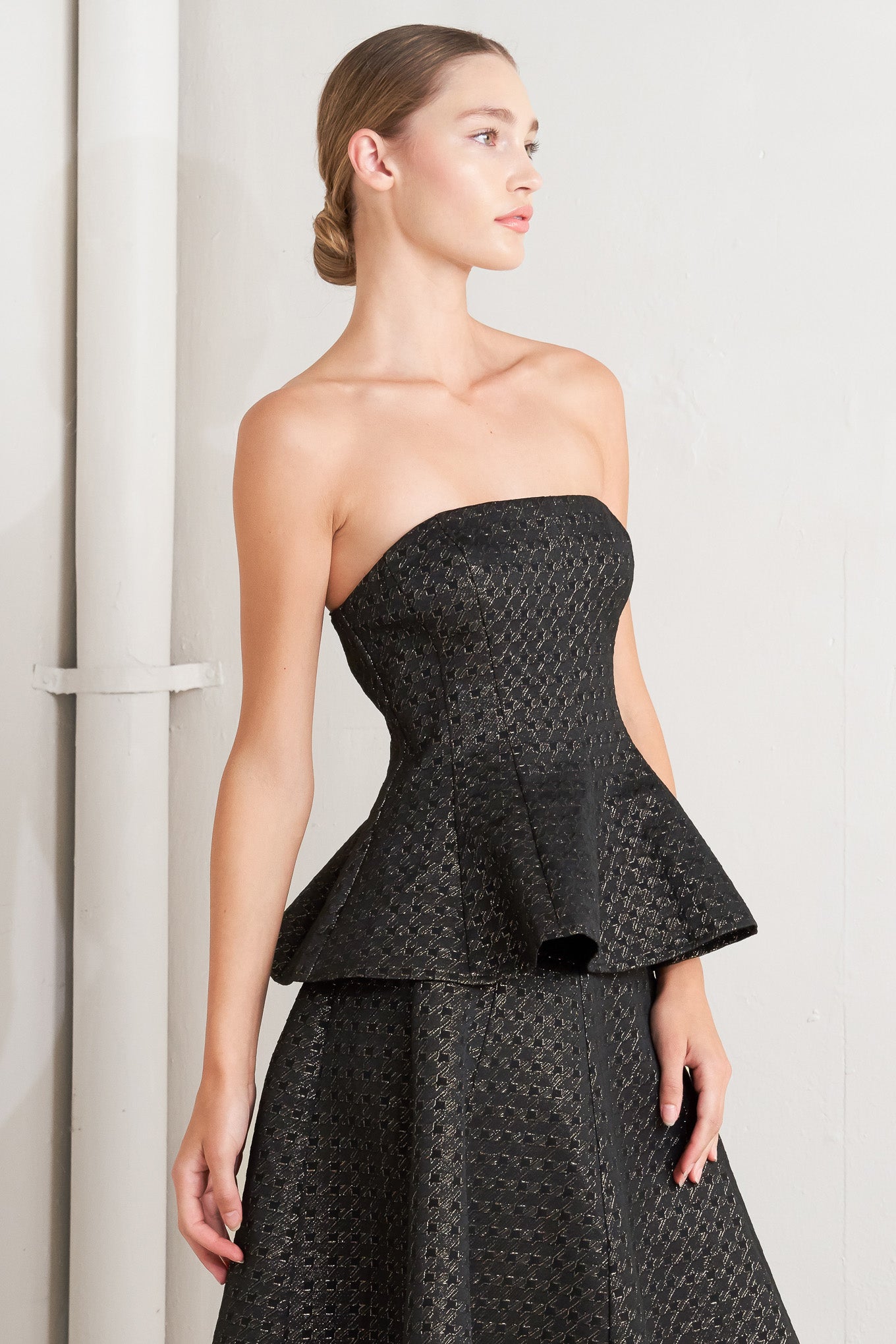 A textured metallic threaded woven top featuring strapless, peplum and back zipper closure.