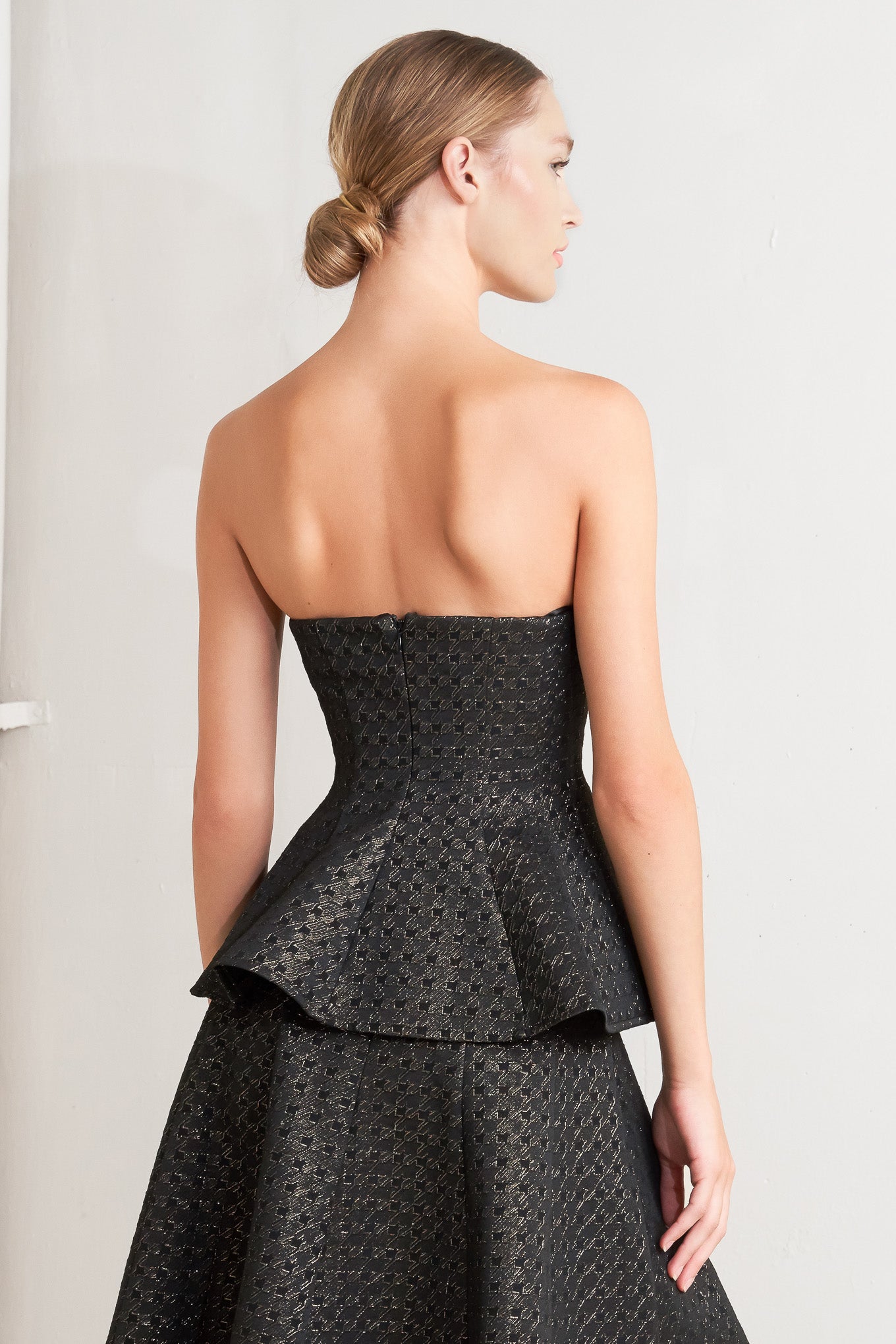 A textured metallic threaded woven top featuring strapless, peplum and back zipper closure.