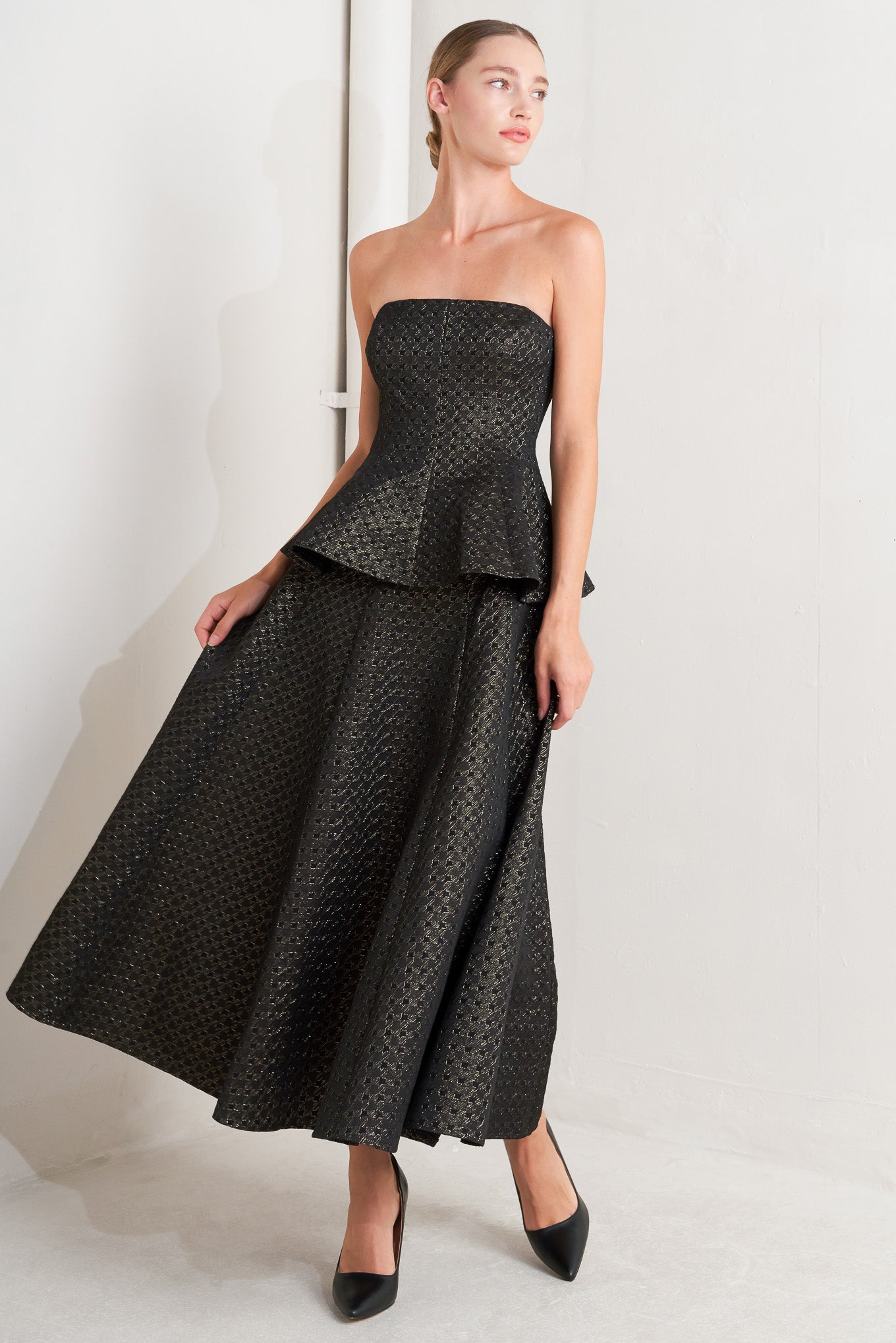 A textured metallic threaded woven top featuring strapless, peplum and back zipper closure.