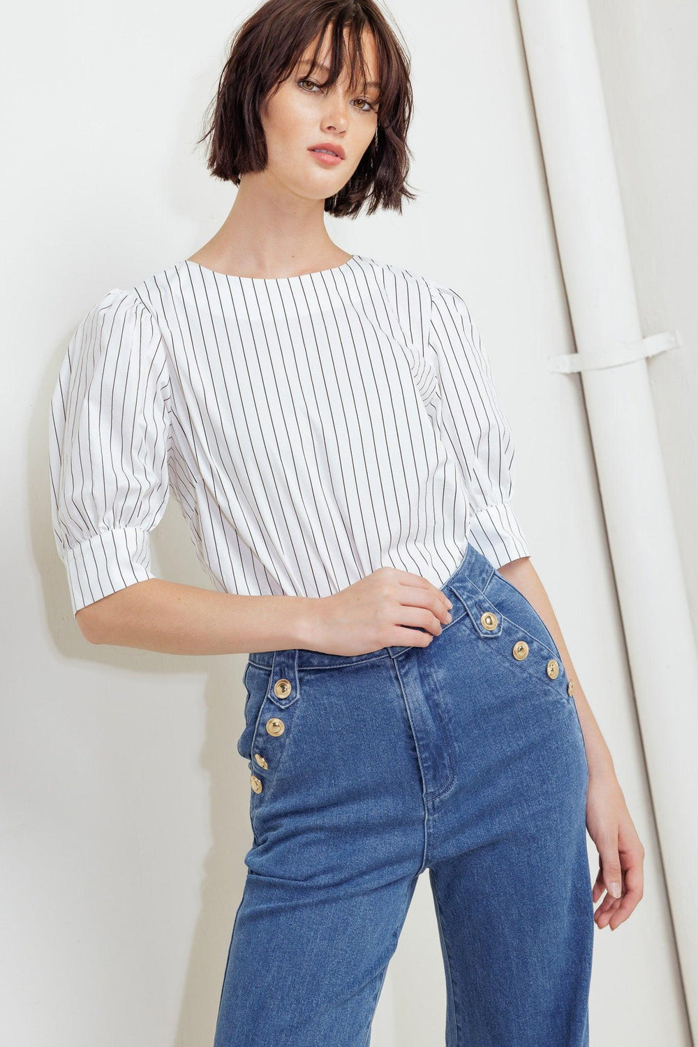 A striped woven top featuring round neckline, short puff sleeve with cuff and back button down closure