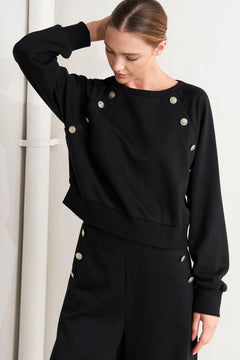A solid woven top featuring crew neckline, long sleeve and button detail