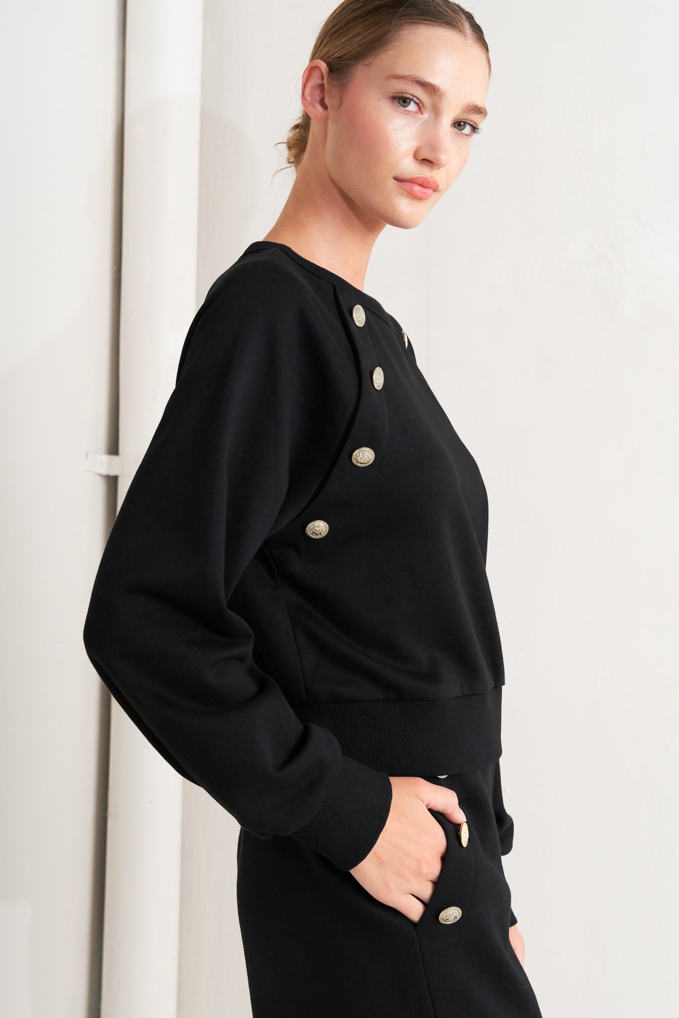 A solid woven top featuring crew neckline, long sleeve and button detail