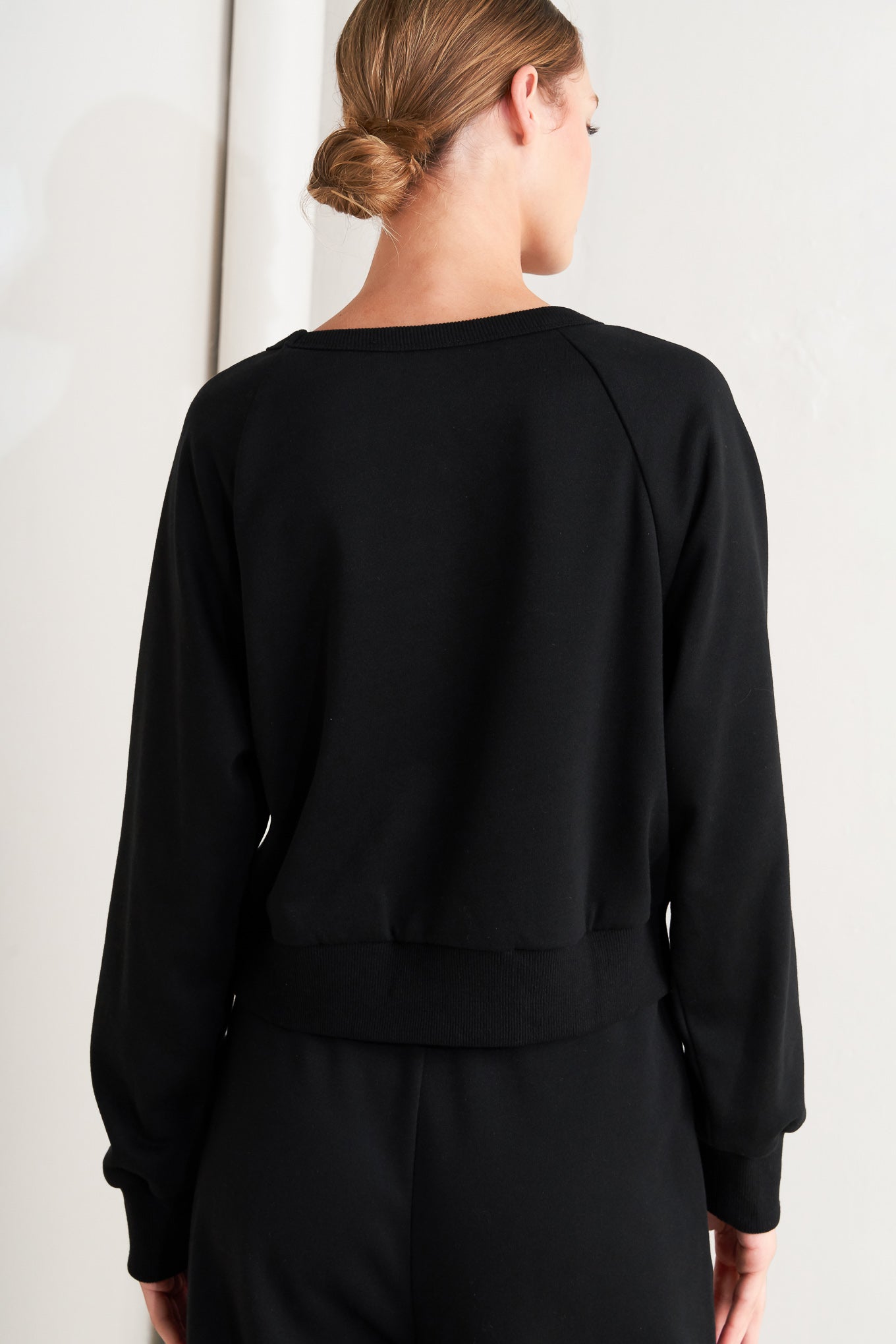 A solid woven top featuring crew neckline, long sleeve and button detail