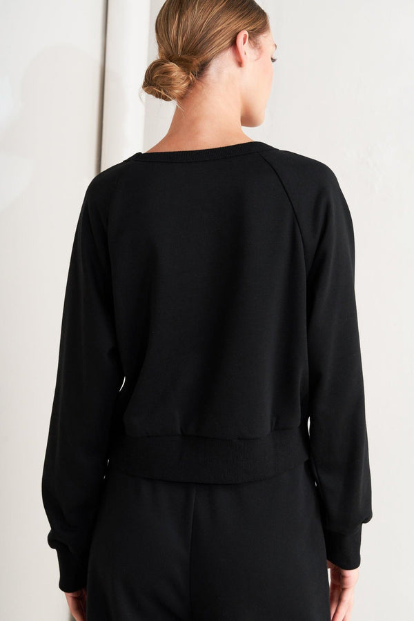 A solid woven top featuring crew neckline, long sleeve and button detail