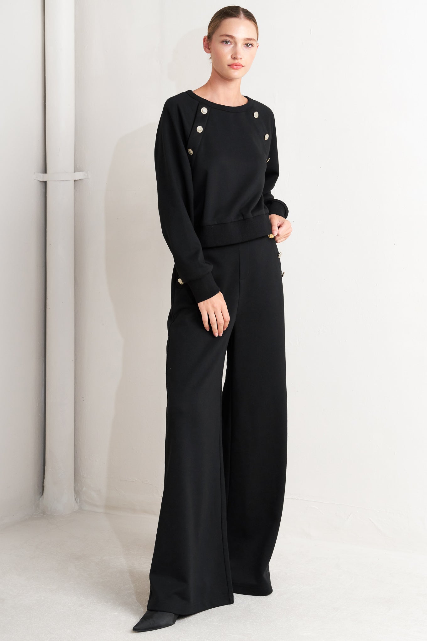 A solid woven top featuring crew neckline, long sleeve and button detail
