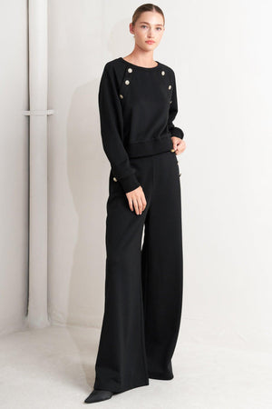 A solid woven top featuring crew neckline, long sleeve and button detail