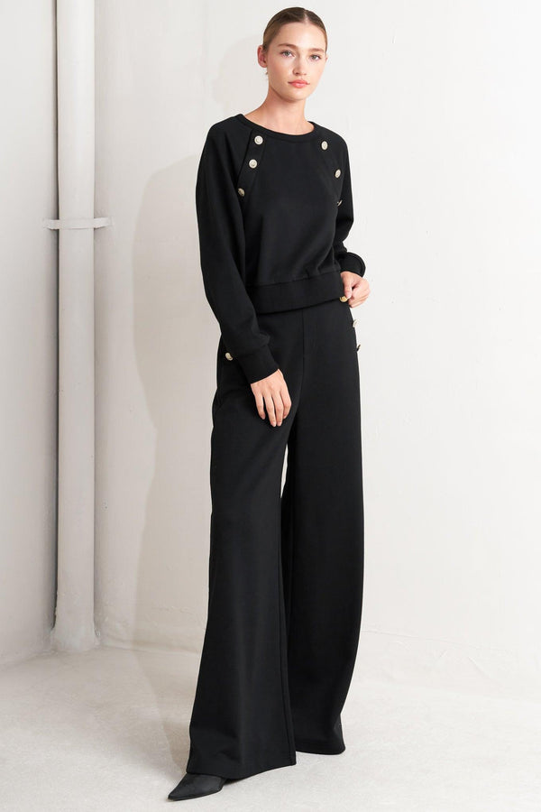 A solid woven top featuring crew neckline, long sleeve and button detail