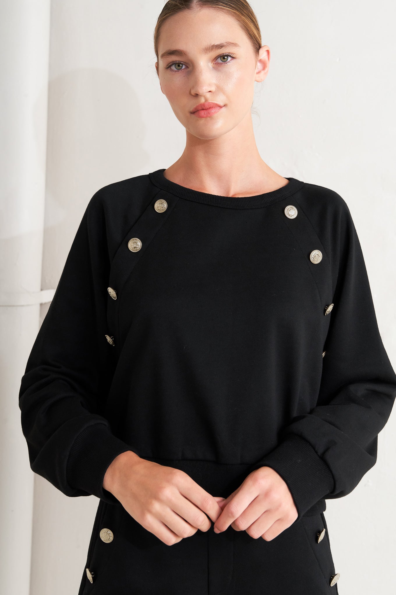 A solid woven top featuring crew neckline, long sleeve and button detail