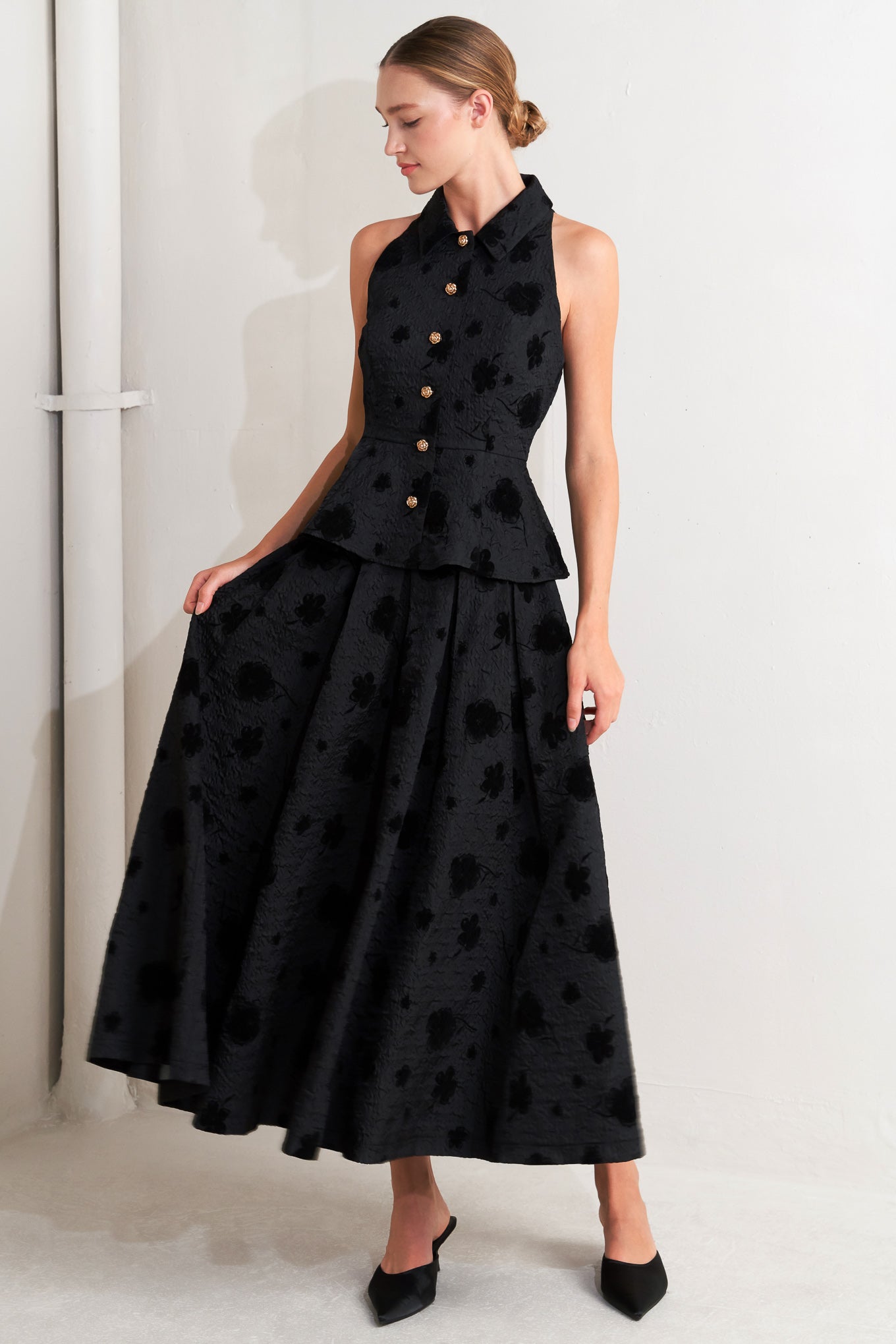A textured woven top featuring collar, sleeveless, front button closure and peplum.