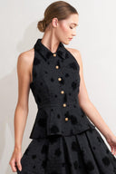 A textured woven top featuring collar, sleeveless, front button closure and peplum.