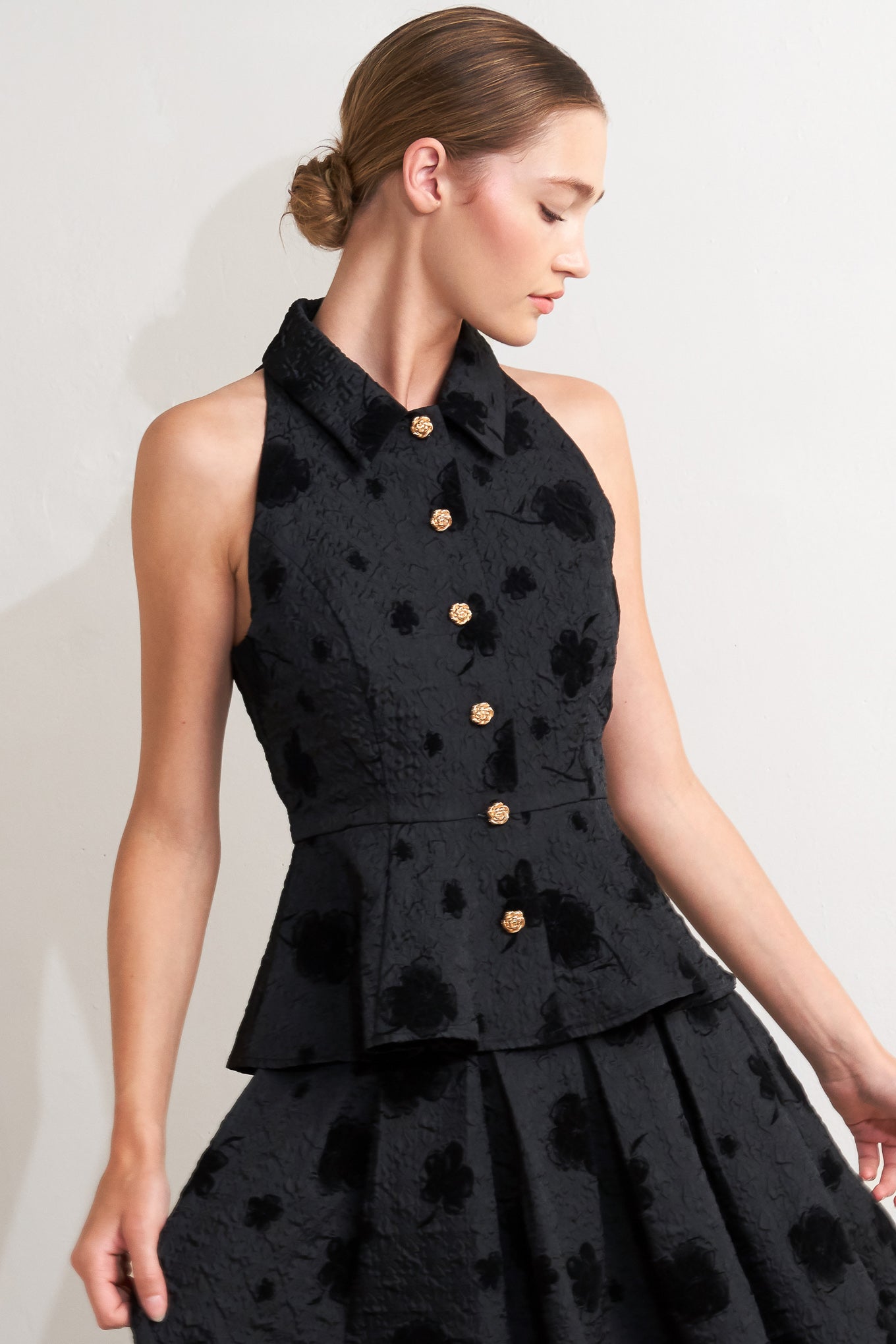 A textured woven top featuring collar, sleeveless, front button closure and peplum.