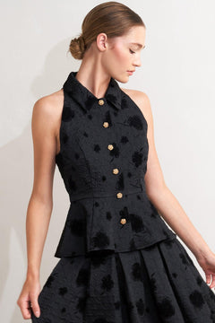 A textured woven top featuring collar, sleeveless, front button closure and peplum.