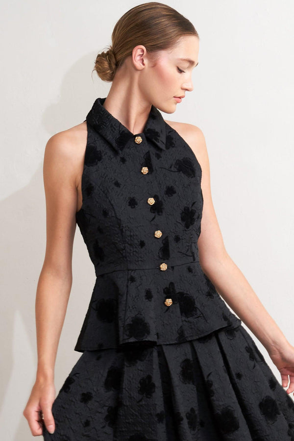 A textured woven top featuring collar, sleeveless, front button closure and peplum.