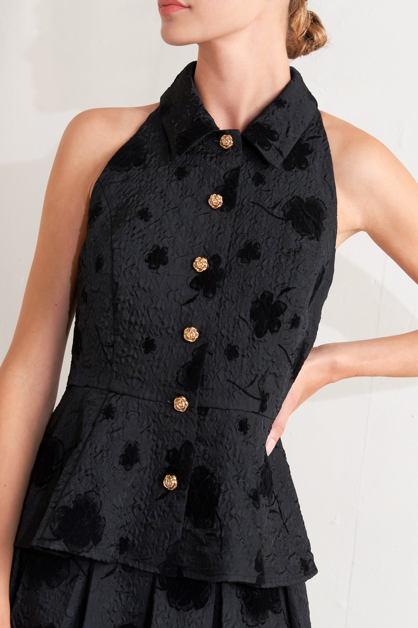 A textured woven top featuring collar, sleeveless, front button closure and peplum.