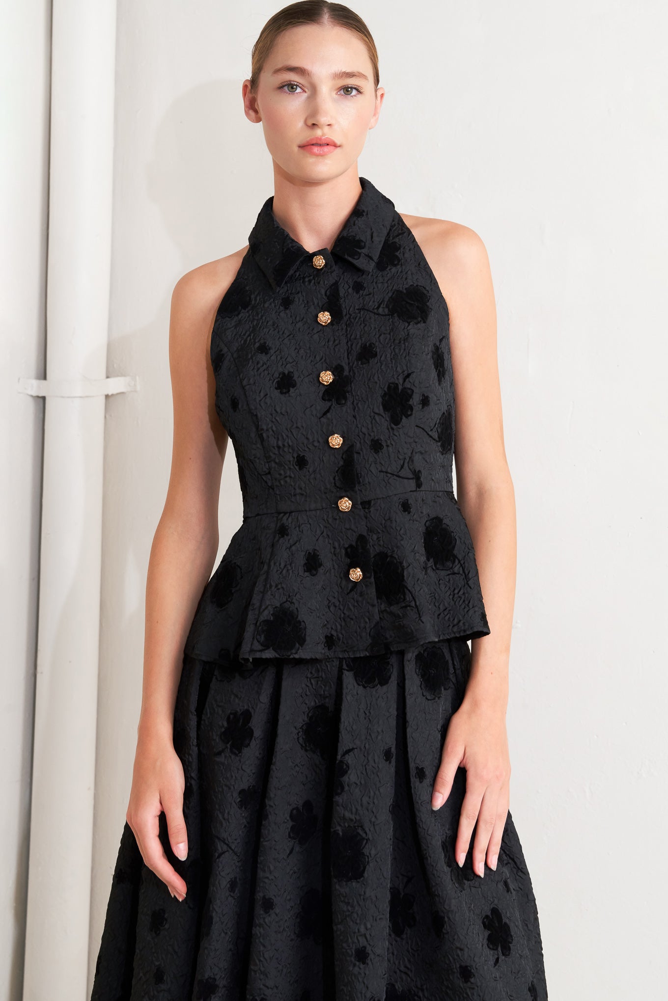 A textured woven top featuring collar, sleeveless, front button closure and peplum.