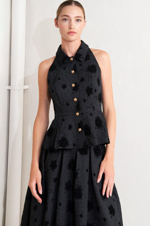 A textured woven top featuring collar, sleeveless, front button closure and peplum.