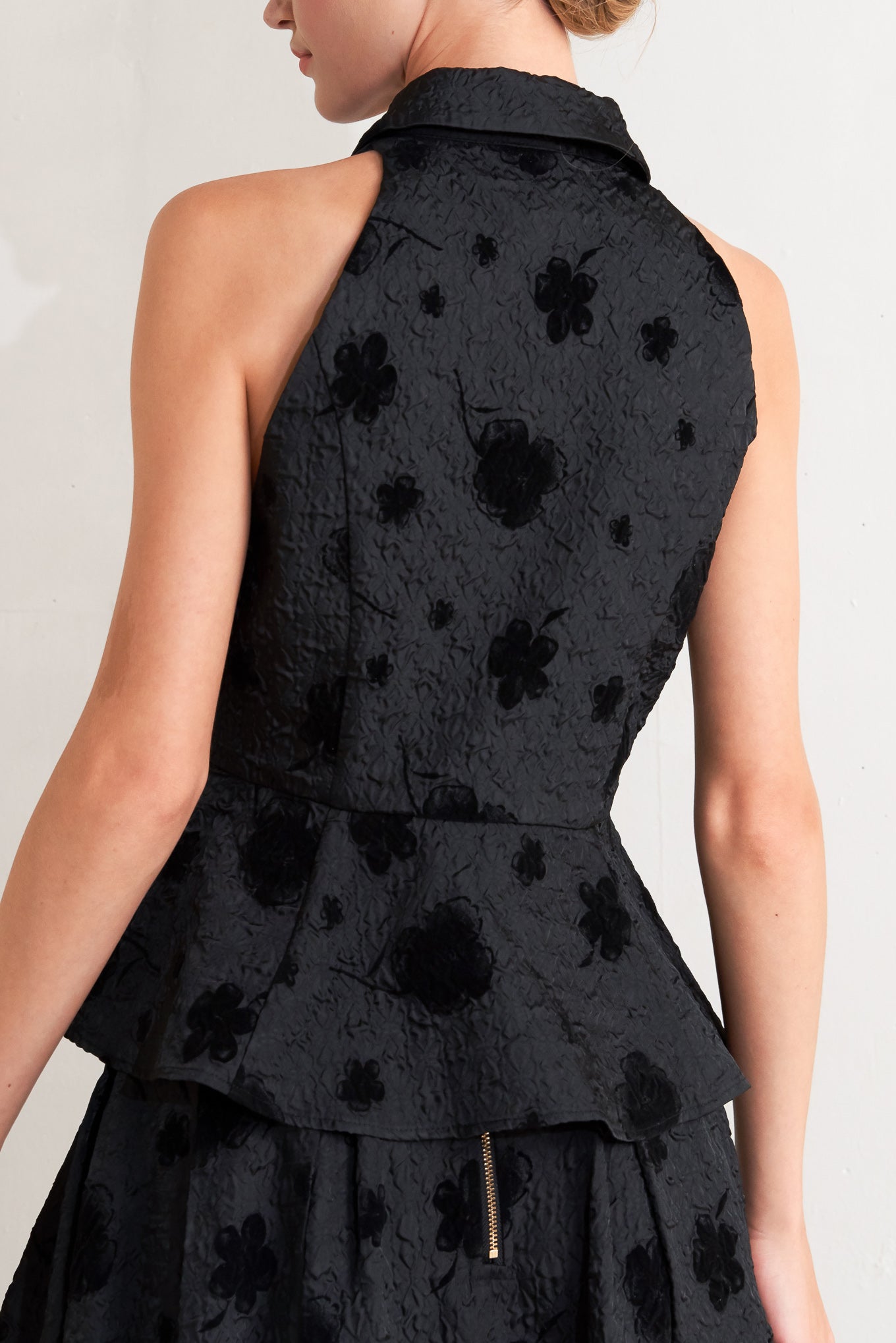 A textured woven top featuring collar, sleeveless, front button closure and peplum.