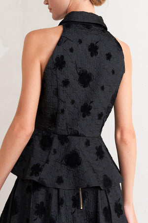 A textured woven top featuring collar, sleeveless, front button closure and peplum.