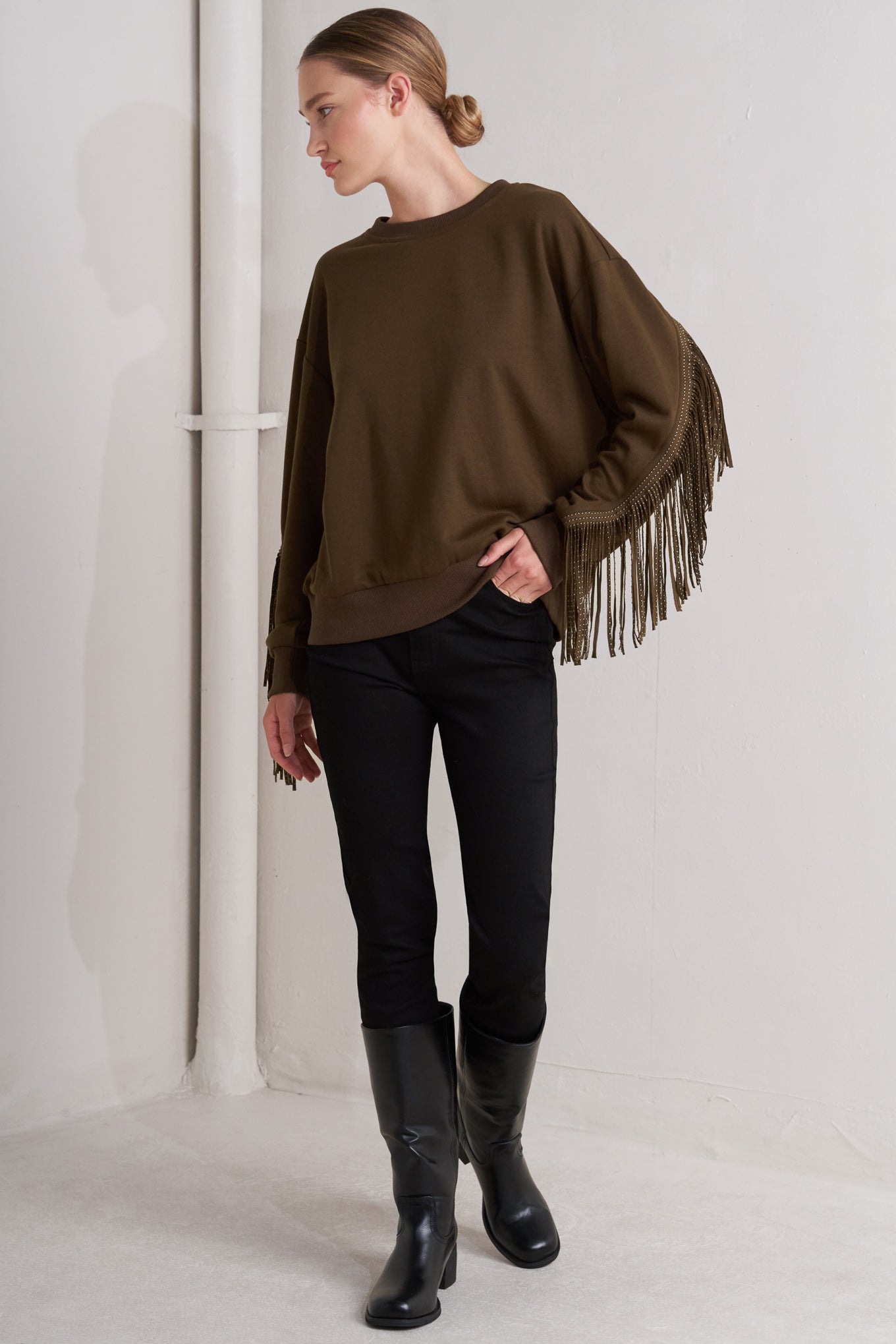 A pullover knit top featuring crew neckline, long sleeve and stud embellished fringe back detail