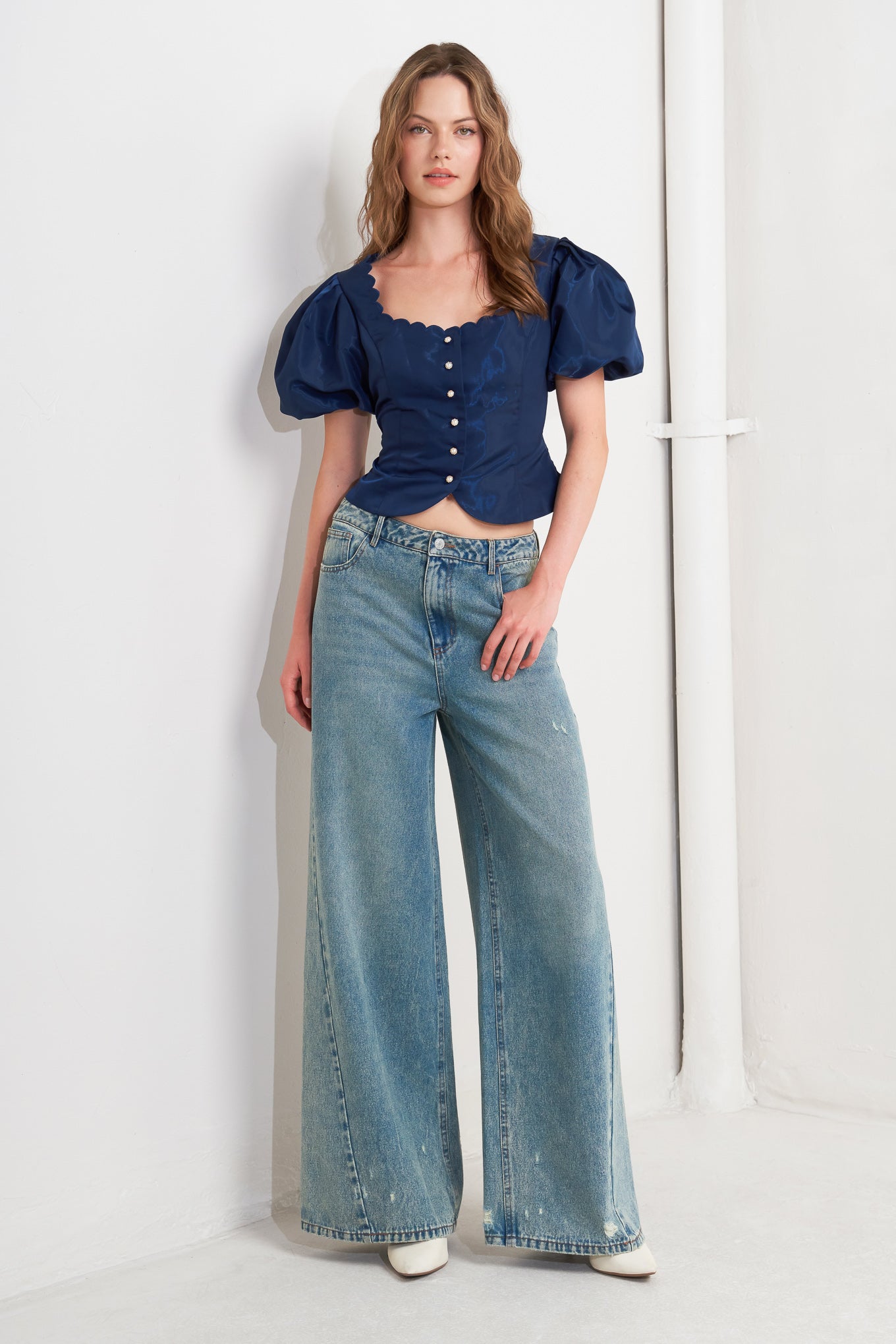 A solid woven top featuring scalloped edge square neckline, short puff sleeve and front button down