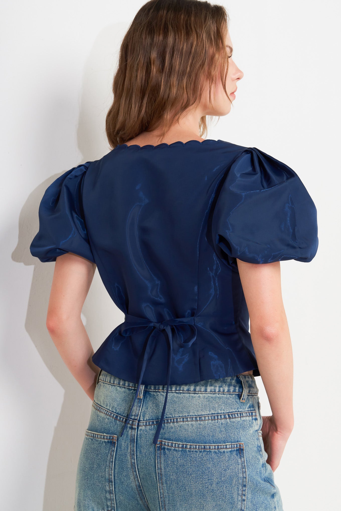 A solid woven top featuring scalloped edge square neckline, short puff sleeve and front button down