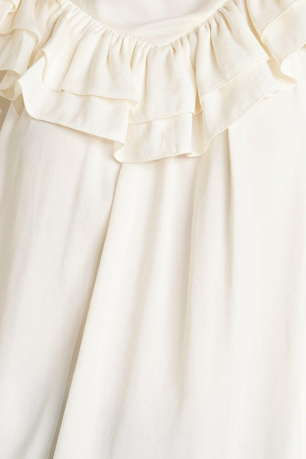 A solid woven top featuring high ruffled neckline, double chevron ruffled front, long sleeve and back neck tie detail