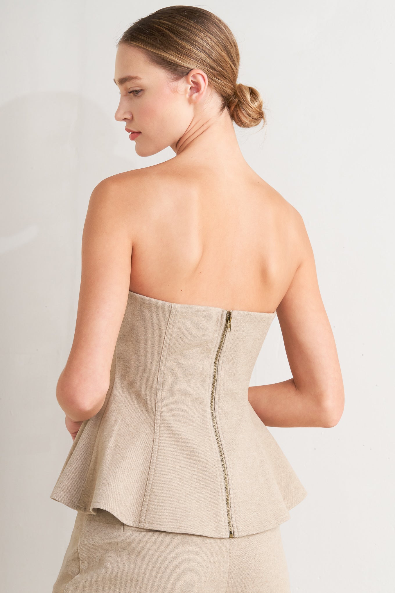 A solid knit top featuring strapless, front button detail and back zipper closure.