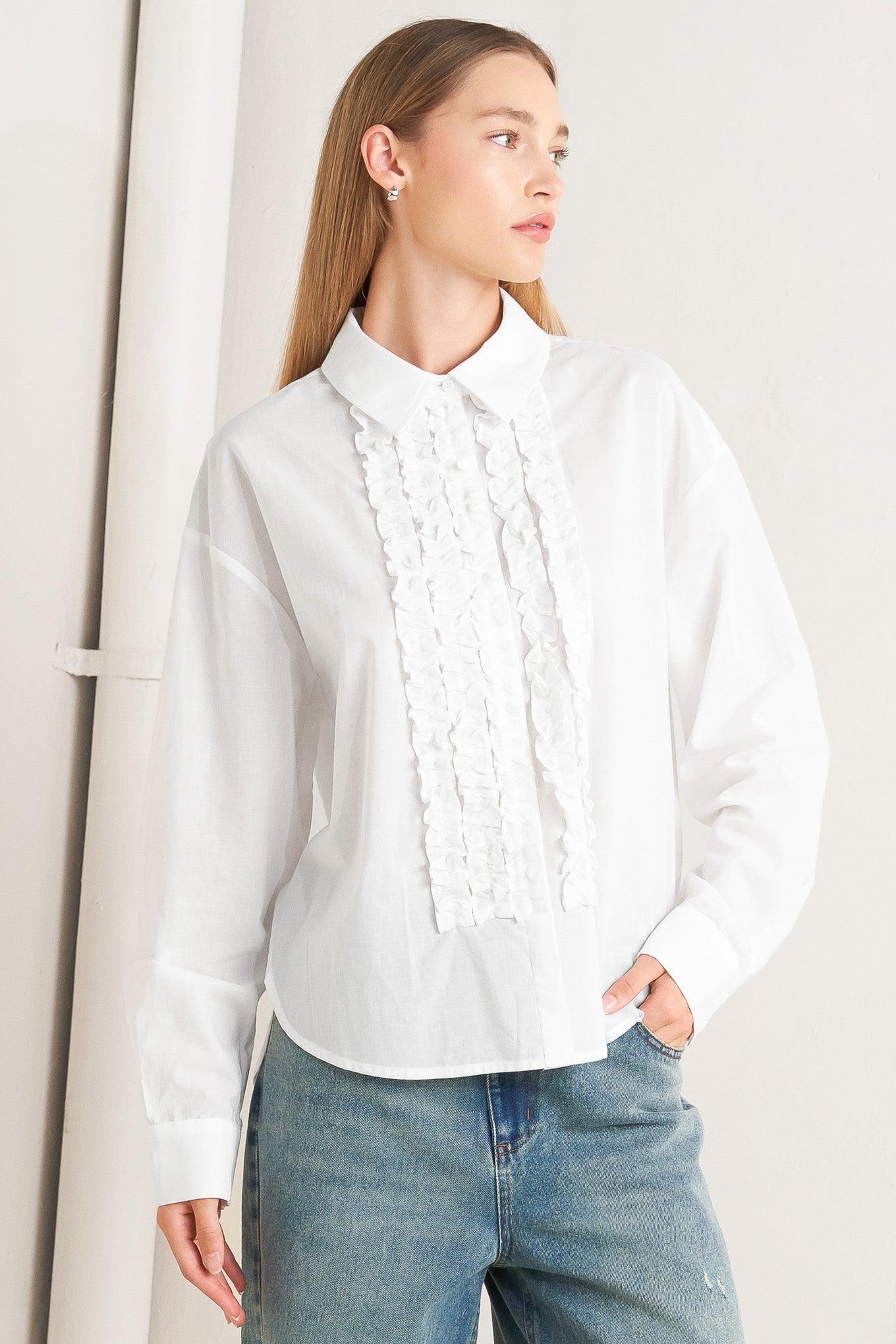 A solid woven top with a collar, button-down front, long sleeves, and front ruffle detail.