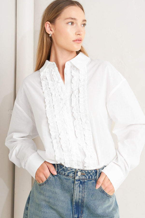 A solid woven top with a collar, button-down front, long sleeves, and front ruffle detail.